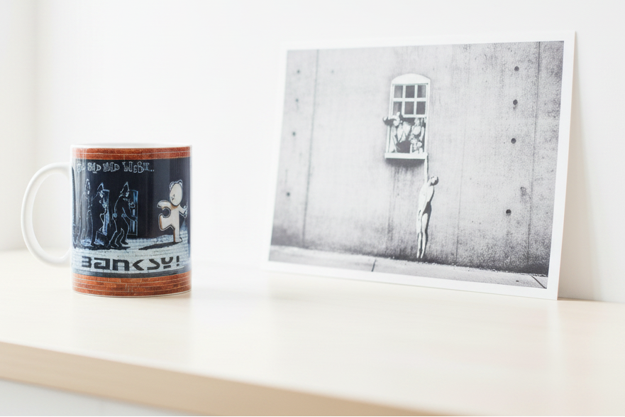 Banksy Mild Mild West ceramic mug in bright lifestyle setting alongside original Banksy artwork print
