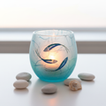 Strawsilk frosted glass ocean fish votive tealight holder glowing warmly with lit candle inside