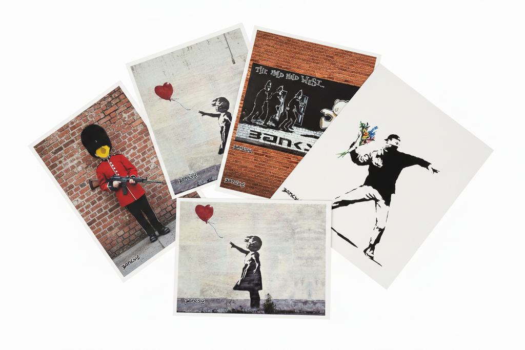 Collection of Banksy art postcards fanned out in a flat lay arrangement on white surface