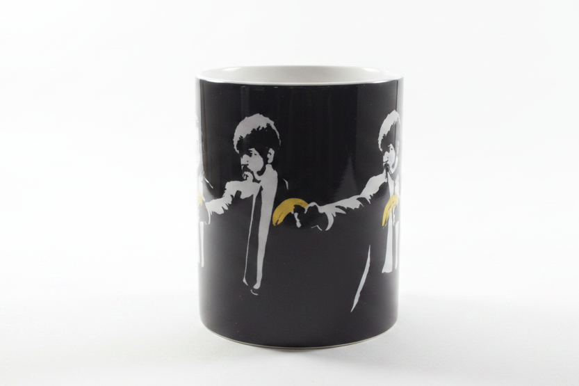 Banksy Pulp Fiction black ceramic mug on clean white surface, bright lifestyle product photography