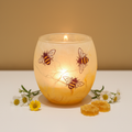 Strawsilk frosted glass busy bees votive tealight holder in cream and amber glowing warmly with lit candle inside