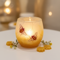 Strawsilk frosted glass busy bees votive tealight holder glowing warmly with lit candle inside