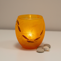 Strawsilk frosted glass amber orange fish votive tealight holder glowing warmly with lit candle inside