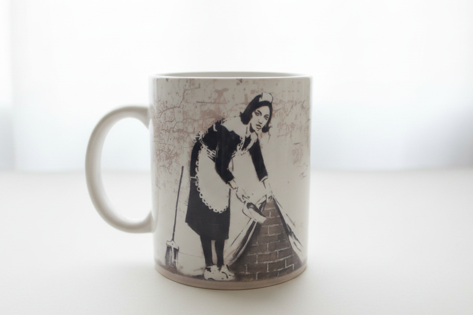 Banksy Maid In London ceramic mug on clean white surface, bright lifestyle product photography