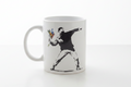 Banksy Love Is In The Air flower thrower ceramic mug on clean white surface, bright lifestyle product photography