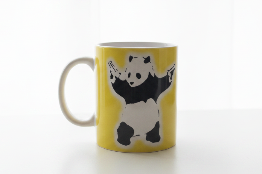 Banksy Panda With Guns yellow ceramic mug on clean white surface, bright lifestyle product photography
